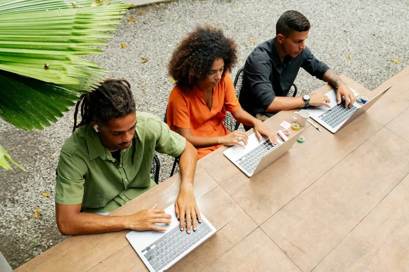 Three people working together with laptops at a shared table